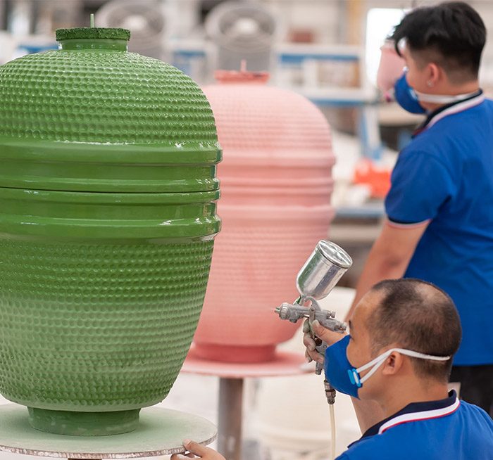 Worker applying glaze to a ceramic kamado grill